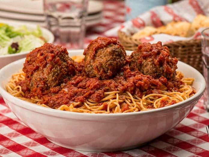 Three of Buca's famous meatballs perched on top of a bowl of spaghetti in a Buca di Beppo restaurant